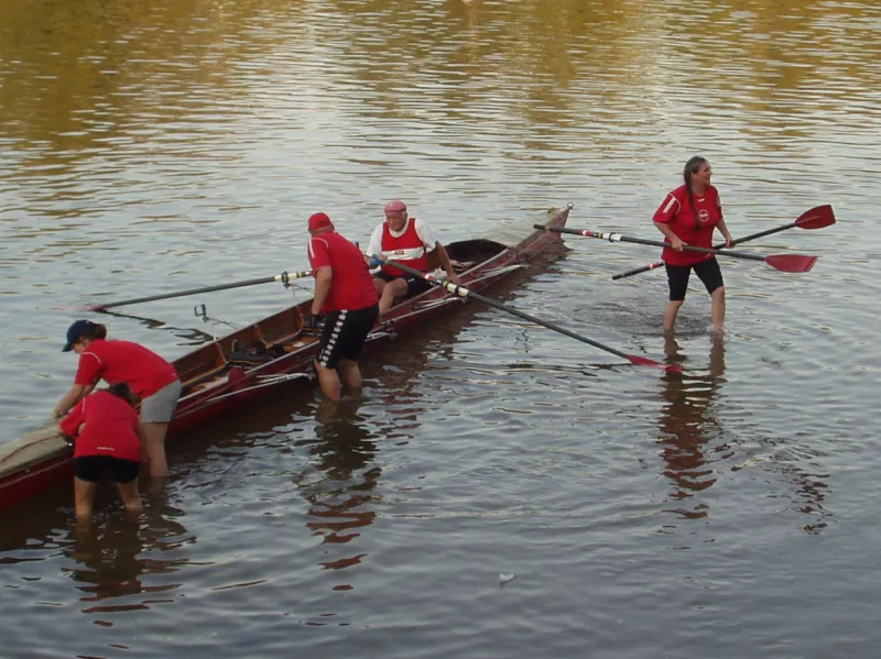 FRGS-Crew in roten Trikots beim Anlegen des Ruderbootes am Mainufer