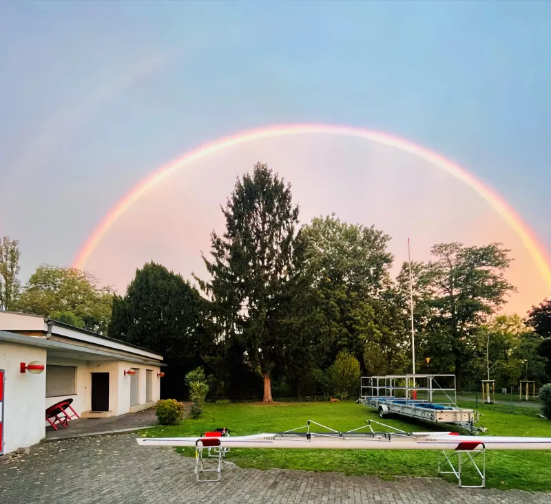 Doppelter Regenbogen über Bootshaus und Garten der FRGS, davor ein Rennvierer auf Böcken